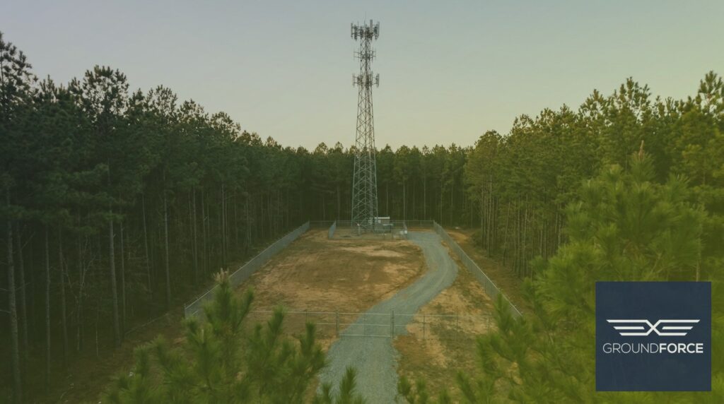 A cell tower compound in Georgia with cleared vegetation around the base, perimeter fence, and access road.