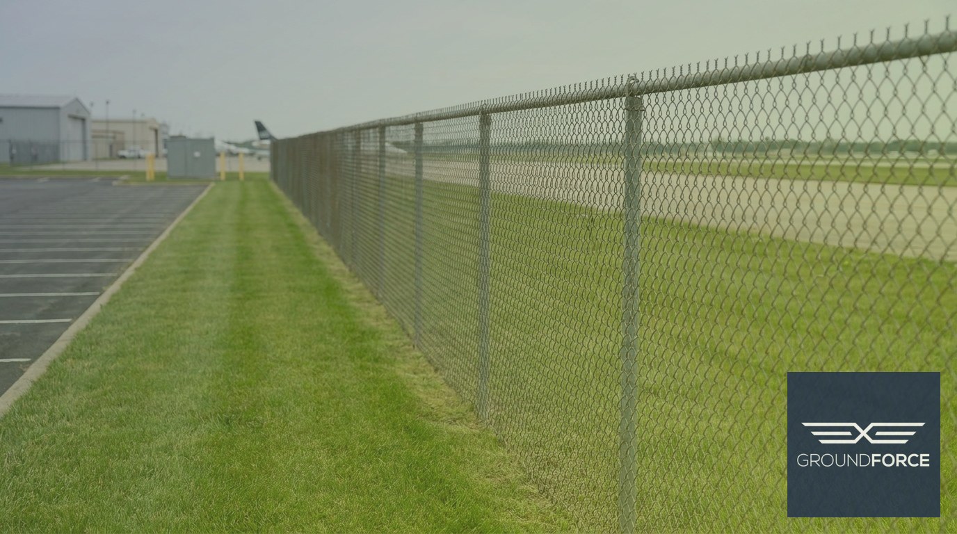 Airport perimeter security fence dividing the public landside grounds from the secured airside area.